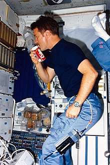 Astronaut Tony England drinking Coca-Cola from a special can designed for zero gravity. NASA shuttle astronaut drinks from a specially designed Coke beverage can.jpg