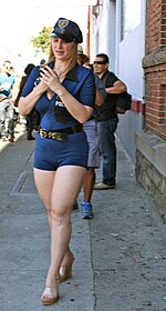 A woman performs sexual roleplay using fetishized uniform of a lady cop, at Folsom Street Fair. Police woman to protect and serve folsom street fair, san francisco (2012) (8020168303).jpg