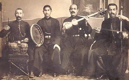 Mugham performer khananda Seyid Shushinski and his ensemble of 3 other men holding musical instruments