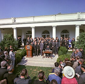 President Lyndon B. Johnson signed the Poverty Bill (also known as the Economic Opportunity Act) while press and supporters of the bill looked on, August 20, 1964. Signing of the EOA.jpg