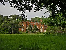 Kleurenfoto van een groot landhuis in een park