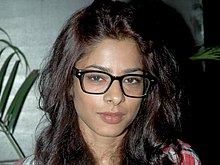 Portrait picture of Sugandha Garg at Aarakshan movie media preview. Her brunette hair is loose over her shoulders and she is wearing black rimmed 'Clark Kent' style glasses.