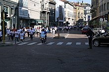 A police officer on a motorcycle leads runners of all ages down a city street