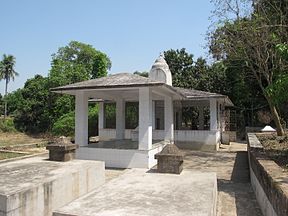 Uma estrutura de pedra semelhante a um gazebo, telhado piramidal e uma pequena cúpula