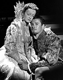 Photographie d'une actrice habillée en Élisabeth et d'un homme lui tenant les mains, sa tête appuyée sur son épaule.
