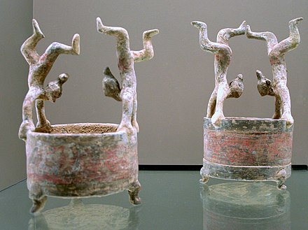 Two black-and-red painted, footed ceramic wares decorated with acrobat figurines, each one balancing himself on both hands, dated to the Western Han Era