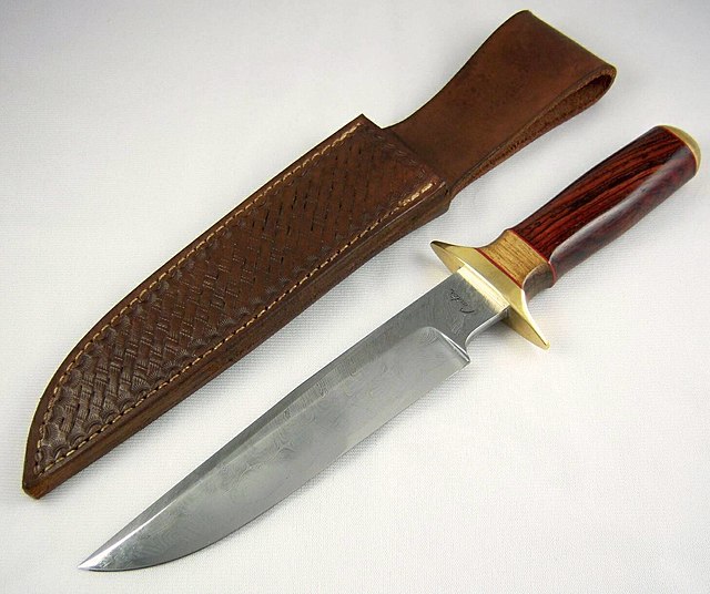 Large knife with polished wooden handle, close to a leather sheath