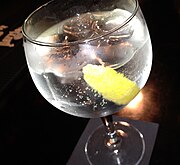 A gin and tonic with ice and lemon wedge