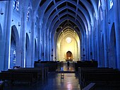 Fotografia colorida de nave de igreja com nervuras de concreto azulado.