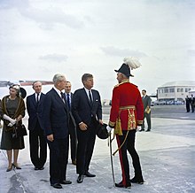 Major-General Sir Julian Gascoigne greeting President of the United States John F. Kennedy, at the American Kindley Air Force Base on St. David's Island, with Prime Minister of the United Kingdom Harold Macmillan, Foreign Secretary the 14th Earl of Home, and British Ambassador to the United States Sir David Ormsby-Gore, December 1962. KN-C19778 President John F. Kennedy Arrives in Bermuda.jpg