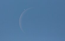venus next to a crescent moon in the blue daytime sky