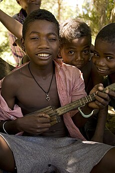 Malgas fiú kabosyn, egy mandolinhoz hasonló hangszeren játszik