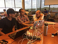 Three people around a laptop