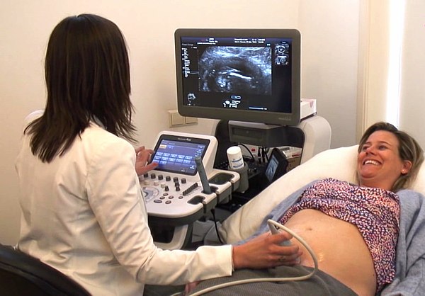 A pregnant woman receives an ultrasound examination from a midwife sonographer