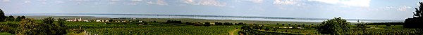 Panoramabild des Neusiedler Sees von Westen in den Weinbergen über Rust aufgenommen. Der Standort gewährt einen Blick bis weit hinein in die Ungarische Tiefebene (Kisalföld). Links die Stadt Rust, rechts die Gegend von Mörbisch