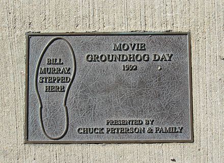 A floor-positioned plaque in Woodstock, Illinois commemorating the pothole Bill Murray's character steps in during Groundhog Day