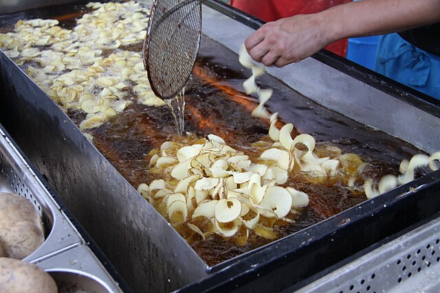 Homemade potato slices are deep fried in hot oil for several minutes.