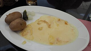 Raclette servie avec des pommes de terres et des petits oignons.
