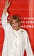 Jeanne Moreau in front of a red background, waving