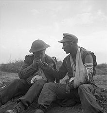 A wounded soldier from the Durham Light Infantry shares a cigarette with a wounded German prisoner during the Mareth line battle, 22-24 March 1943. The British Army in Tunisia 1943 NA1344.jpg