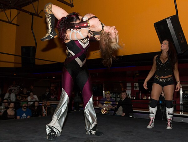 Vanessa Kraven holds Xandra Bale in the air with a Canadian backbreaker rack.