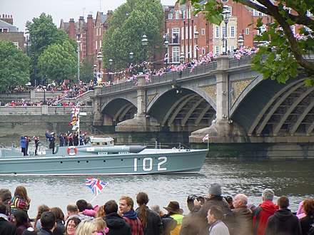 Spectators lined the embankments. World War II British coastal warship MTB 102 passes under Battersea Bridge.