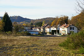 Uma estrada ladeada por duas fileiras de casas com uma grande colina ao fundo.