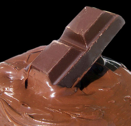 A chocolate bar and molten chocolate. Chocolate is made from the cocoa bean, which is a natural source of theobromine.
