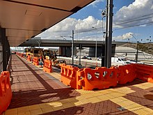 Train station platform with construction barriers on the platform and machinery on tracks