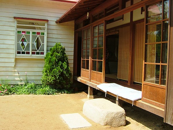 Cushions on an engawa protected by sliding glass doors. Note fume-ishi, stone step.