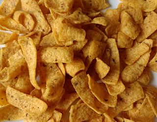 Corn chip snack food made from cornmeal, either fried in oil or baked