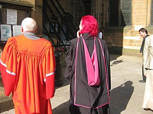 Man and woman wearing Durham and Glasgow PhD gowns, respectively.