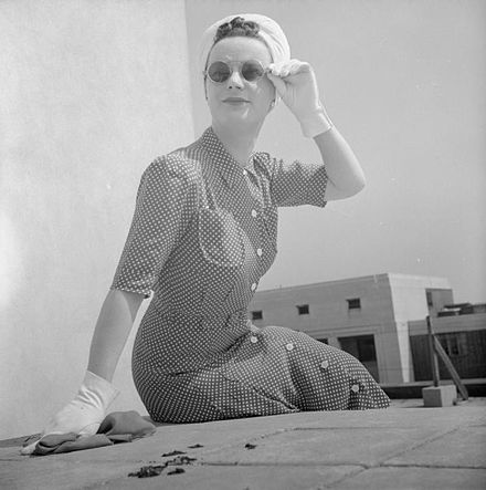 A woman wearing a Utility rayon shirt dress with front-buttoning, 1943