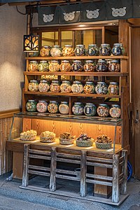 Illuminated wooden shelf with many glass jars containing cookies for sale in Tokyo