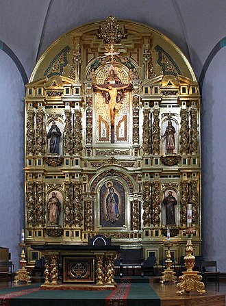 The "Grand Retablo" with the Trinity at top center, St. Junipero Serra top left, St. Kateri Tekakwitha top right, St. Francis bottom right, St. Joseph bottom left and Our Lady of Guadalupe bottom center Mission Basilica San Juan Capistrano 03.jpg