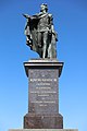 Gustav III:s statue på Skeppsbron i Stockholm. Kongen er iført den svenske skærgårdsflådes uniform hjemvendt fra den russiske krig. Han skænker fredens olivengren til Stockholms borgere. Afsløret i 1808