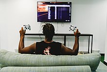 A man posing with two game controllers, while playing on his Xbox One Negative-space-man-controls-all-video-games.jpg