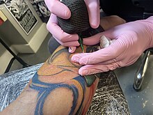 Tattoo artist wearing disposable nitrile gloves during tattooing procedure for hygiene 20-adding white highlights at end.jpg