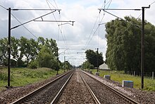 A railway track leading away into the distance with overhead electrical catenary