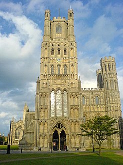 A Catedral de Ely, na Inglaterra, a torre central ocidental e as torres menores emolduradas tinham características de transição, década de 1180.  A torre da esquerda caiu.  alpendre gótico, década de 1250;  lanterna, década de 1390.