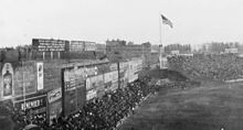 The original ad-covered Green Monster in 1914, with "overflow" fan seating in front of the wall's base, atop "Duffy's Cliff" (seen in the distance, nearest the flagpole) Green Monster 1914.jpg