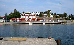 Porto de Grisslehamns, com o terminal de balsas (o prédio vermelho) e o Hotell Havsbaden (o prédio branco atrás).