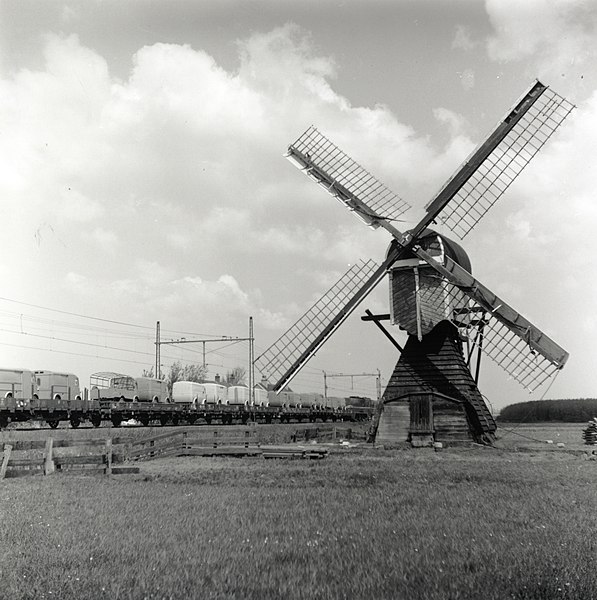 File:HUA-167017-Afbeelding van een passerende goederentrein beladen met bestelauto s ter hoogte van Lisse met op de voorgrond een wipwatermolen.jpg