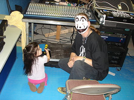 A man in Juggalo face paint next to a small child