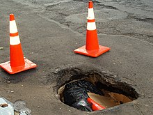 A deep pothole with a nearby patched area on New York City's Second Avenue Large pot hole on 2nd Avenue in New York City.JPG