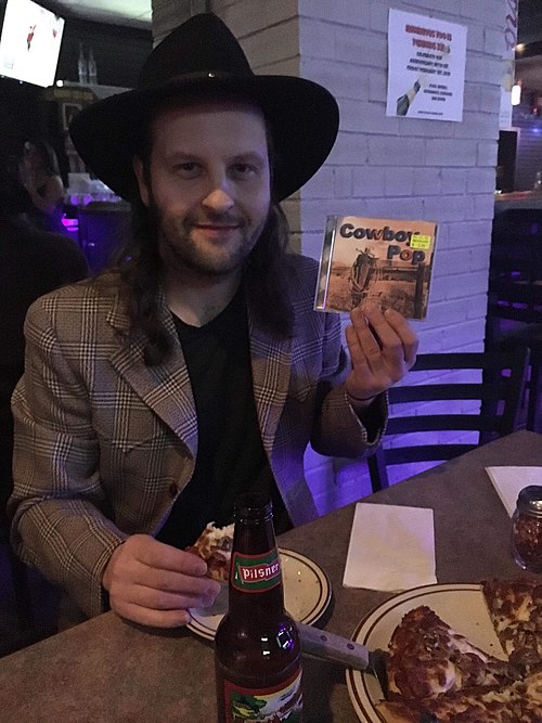 A cowboy pop fan shows off a rare CD at a music festival.