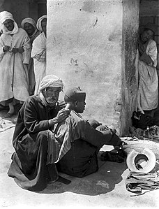 A barber-surgeon shaving, cupping and anointing the back of the neck of a patient; c. 1930s