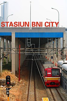 A KRL Commuterline train passing through the BNI City railway station TM 6133F at BNI City Station, Jakarta.jpg