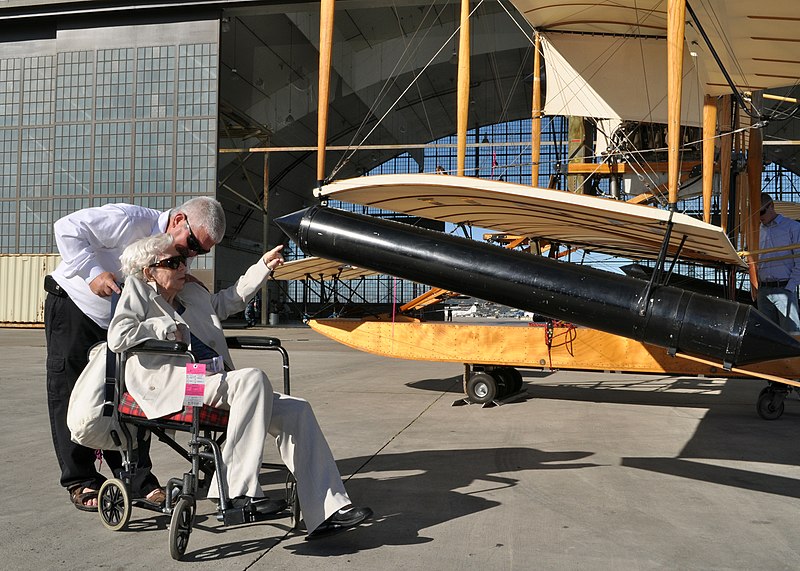 File:US Navy 110211-N-2688M-013 Elizabeth Gordon Ellyson Carmichael, reaches to touch a functional replica of a Curtiss A-1 Triad seaplane as her son, M.jpg