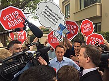 Sharma holding a press conference during the 2018 Wentworth by-election, surrounded by Stop Adani protesters Wentworth by-election Dave Sharma attracts some -StopAdani volunteers on election day 20 October 2018 (45387618852).jpg